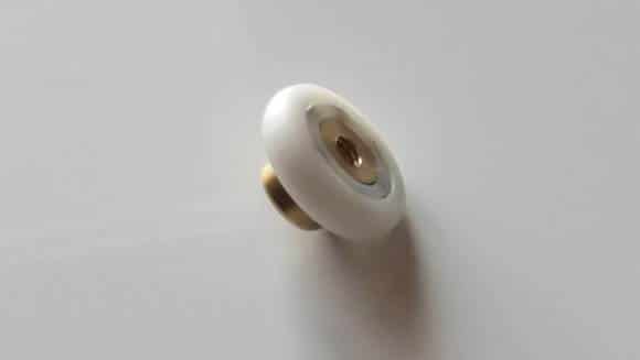 c'est une roulette pour glissière, elle est composée d'une bague en plastique avec un roulement à billes en son centre, un trou taraudé permet de la visser à une porte de douche ou cabine de douche